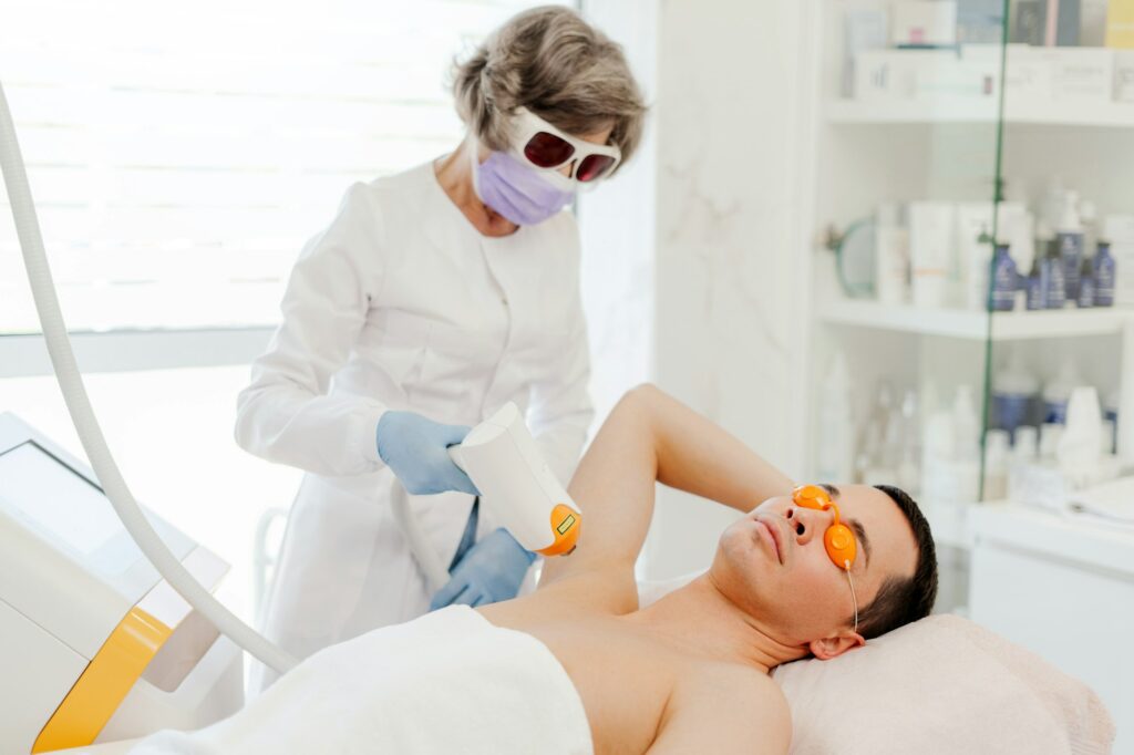 Attractive, mature woman, doctor cosmetologist using laser, removing armpit hair