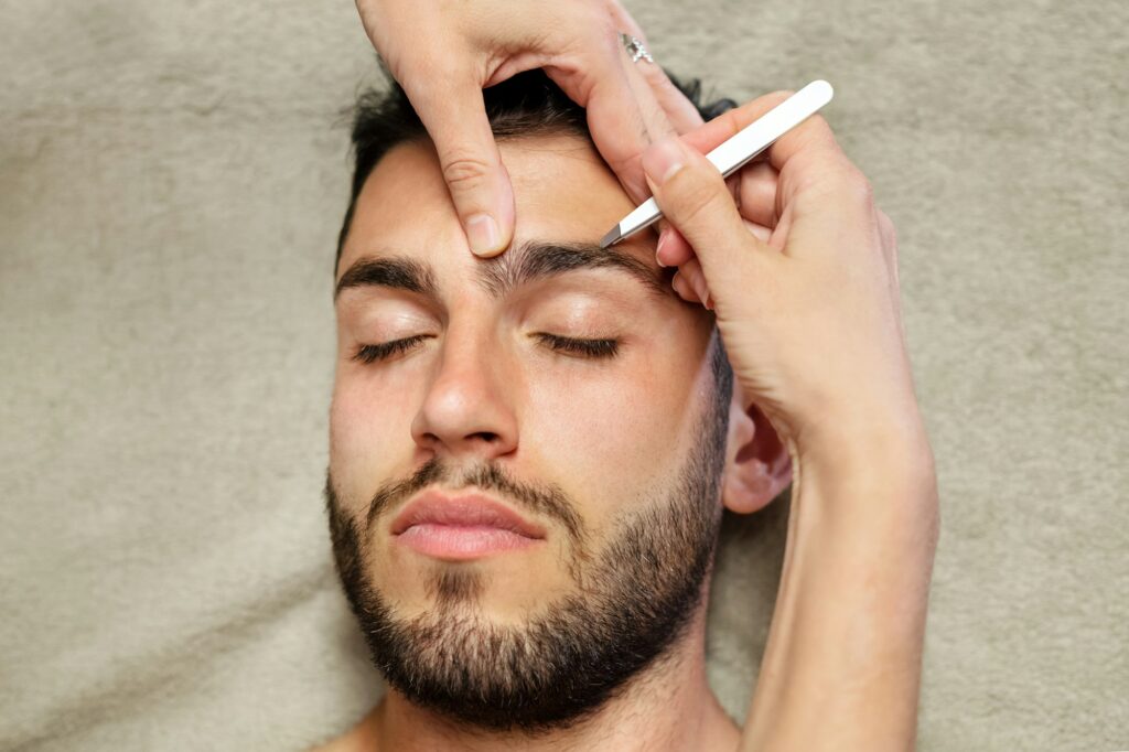 Crop woman plucking eyebrows of man