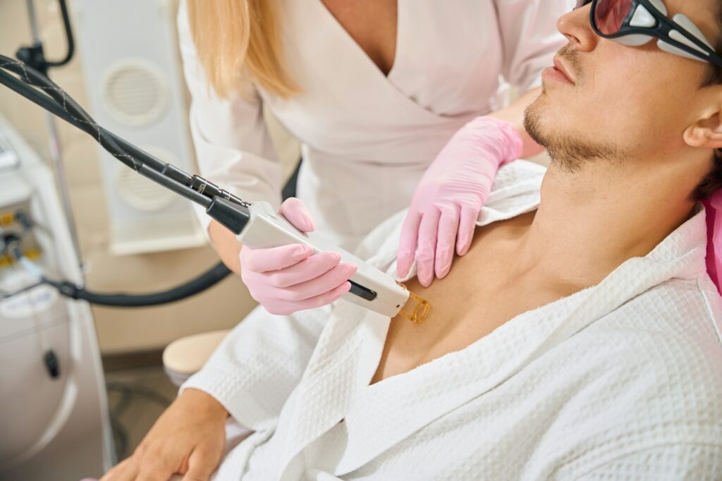 Man undergoes laser hair removal of chest in beauty salon